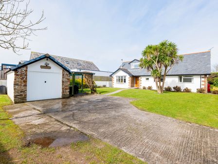 A driveway leading to a detached garage and a white house with a gray roof and a tree on the lawn at Silverdale in Rock