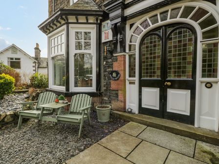 A house entrance with two green wooden chairs and a table outside near a black and white door at Hollywood in Windermere