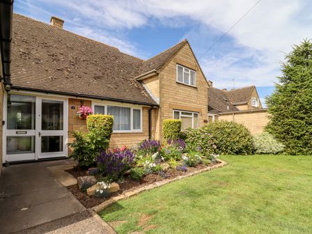 The front of a house with flower beds shrubs and a lawn at 3 Granbrook Lane in Mickleton Gloucestershire