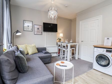 A living room with a sofa and dining area at 24 Baxtergate, Whitby