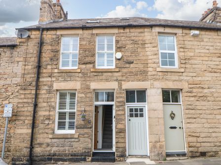 Stone facade of a two story house with three windows a door with stairs visible and two closed doors at Toll House in Corbridge