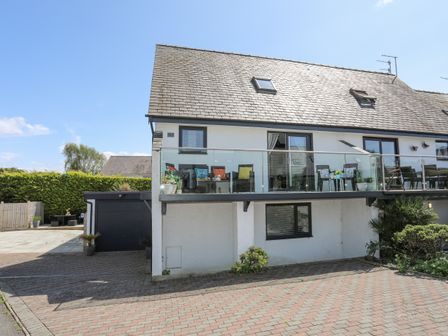 A two-story house with a balcony and outdoor seating at Bywyd Da (232 Cae Du) in Abersoch