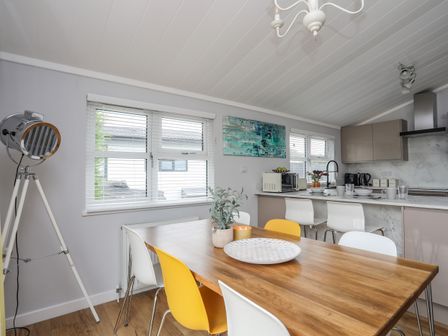 A kitchen and dining area with a wooden table surrounded by white and yellow chairs at The Warren K20 in Abersoch