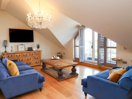 A living room with two blue sofas a wooden coffee table a wooden dresser and a chandelier at 7 Four Seasons in Carbis Bay