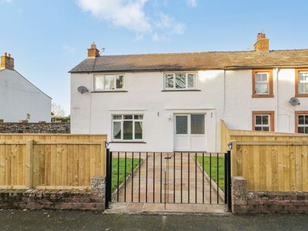 A front view of a white two-story house with a paved pathway and a black metal gate at 1 Springfort Cottages Newton Reigny near Penrith