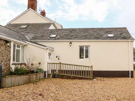 An exterior view of a house with a gravel driveway and a wooden railing at Littleham Court Cottage Littleham near Bideford