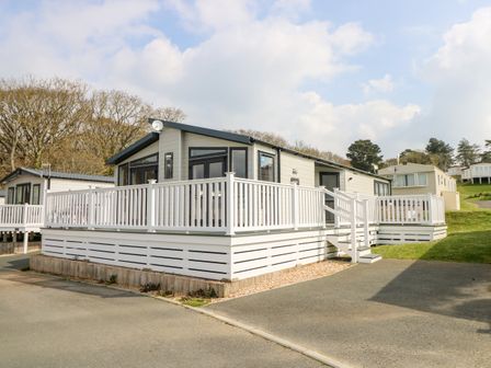 A modern static caravan with a white railing and steps leading to the deck at Crosswinds 67 in Bembridge