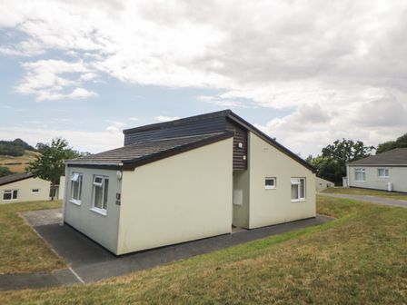 A bungalow with sloped roof and beige walls on a grassy landscape at Harcombe House Bungalow 9 in Chudleigh
