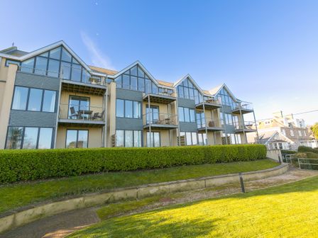Modern apartment building with balconies and large windows overlooking grass and hedges at Puffins in St Ives