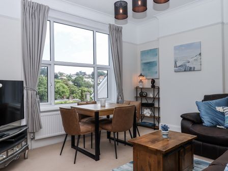 A living room with a dining table and chairs at Kinbrae Apartment in Torquay
