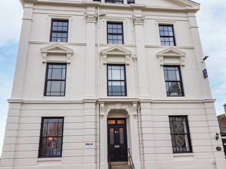 A white multi-storey building with black window frames and a black door labeled No 1 at Number One The Crescent in Filey