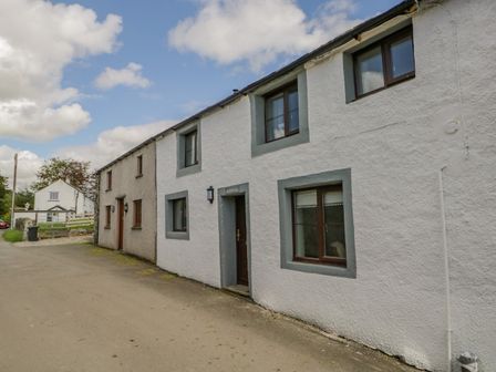 A row of white and beige cottages on a street with windows and doors at Ashness in Bassenthwaite near Keswick