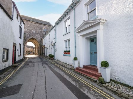 A narrow street with white houses and a stone archway at 1 Tower House in Cartmel