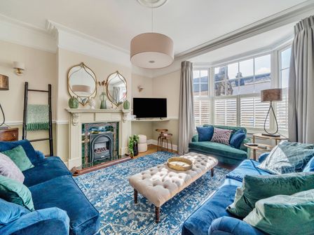 A living room with blue and green sofas a fireplace and a large window at Regatta House in Whitby
