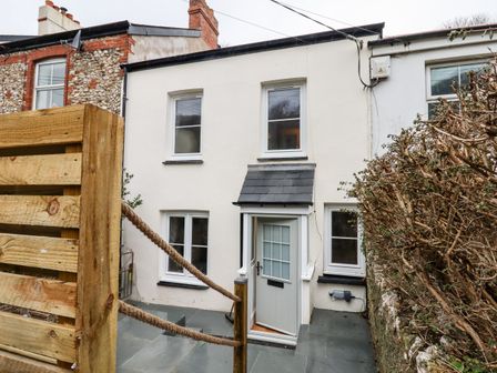 A small two-story house with white walls and a grey door at Beach Road House in Hele Bay Ilfracombe