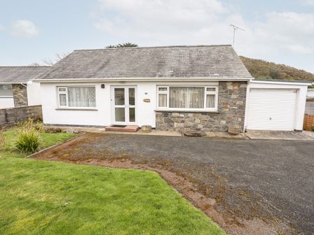 A single-story house with a front lawn driveway and attached garage at Bro Mebyd in Criccieth