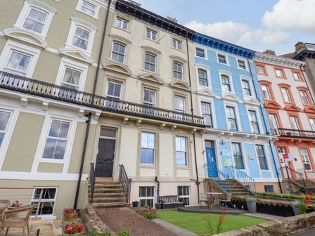 A row of multi story townhouses with different colored facades and outdoor seating areas at Royal View in Whitby