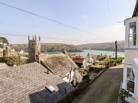A view of rooftops a church tower a river and hills in the background at Driftwood in Fowey