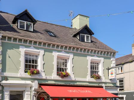A building with a red awning labeled red boat and flower boxes on windows at Above Deck in Beaumaris