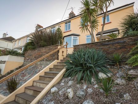 An exterior view of a townhouse with stairs leading to the entrance and landscaped garden at Home in Salcombe