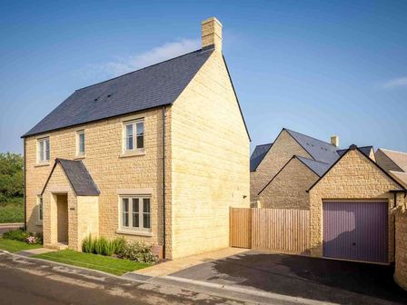 A two story stone house with a slate roof and an attached garage at The Bybrook in Bourton-on-the-Water