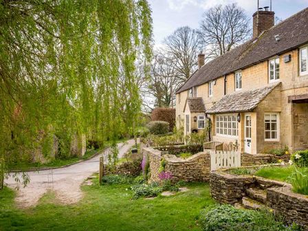 Stone cottages with tiled roofs along a country lane with a stone wall and garden at Willow Cottage in Hampnett nr Bourton-on-the-Water