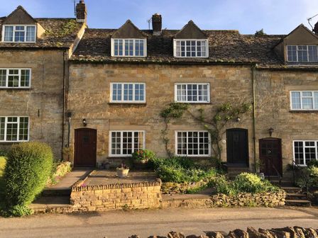 A row of stone cottages with front gardens and trimmed hedges at Willow Vale in Snowshill