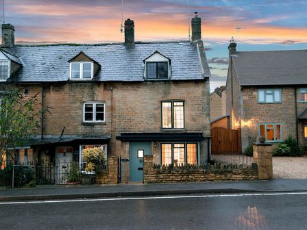 A stone house with two chimneys and windows at sunset at Eastnor in Moreton-in-Marsh