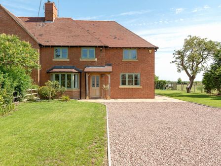 A brick house with green windows a driveway and lawn at Mount View in Childswickham