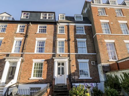 A brick townhouse with white framed windows and a white door with steps leading up to it at Highview in Scarborough