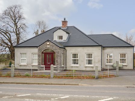 A single story house with a grey roof red front door and metal fence at Sliabh Amharc in Downpatrick