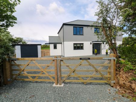 A modern two-story house with a wooden gate and a gravel driveway at Tredarn in Connor Downs