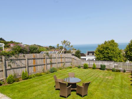 A garden with a table and chairs overlooking the ocean at 65 Channel View Ilfracombe