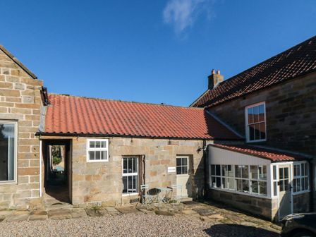 A stone building with a red tiled roof and outdoor seating area at The Nook in Glaisdale