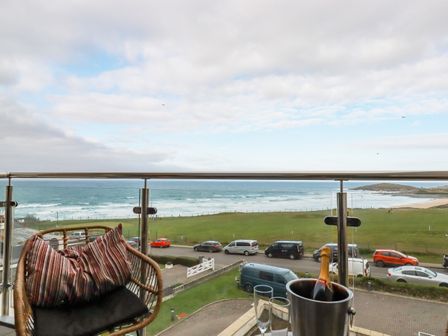 A balcony with a chair and a bottle of champagne in an ice bucket overlooking the ocean at Fistral Retreat in Newquay