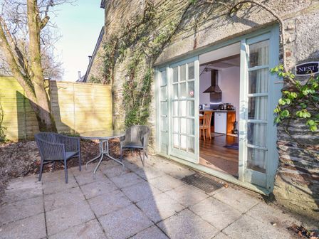 An outdoor patio with a table and chairs at Nest Cottage in St Tudy