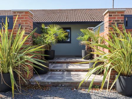 An outdoor entrance area with steps and potted plants between brick pillars at Chalet 1 in Sherburn
