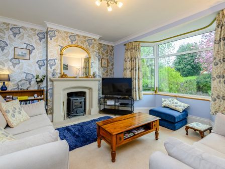 A living room with a fireplace a mirror a wooden coffee table sofas and a large window at Caradoc Tutshill near Chepstow