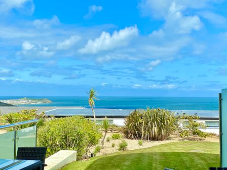 A garden with grass and plants overlooking the sea with a blue sky at Sky in Carbis Bay