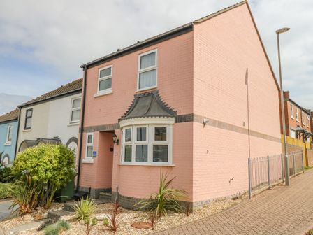A two-story corner house with a pink brick exterior and a bay window at Mermaid House in Brewers Quay Harbour