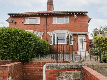 A two story brick house with bay windows a white front door and a fenced front yard at Butter Cross in Scarborough