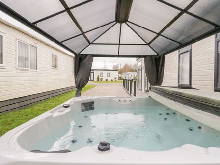 A hot tub with water under a transparent canopy between two buildings at Yealand 36 in Tewitfield