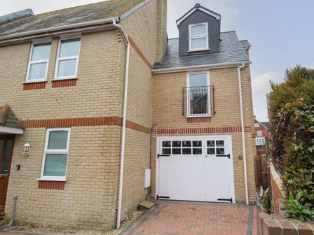 A brick house with white framed windows a white garage door and a paved driveway at Portside Greenhill Weymouth
