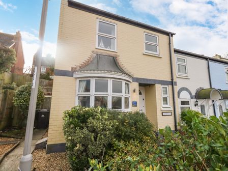 A two-story house with yellow brick facade and bay window with bushes in front at Amaranta Brewers Quay Harbour