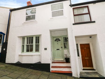 A white building exterior with two doors numbered 6 and 4 and several windows at Oriel Cottage Conwy
