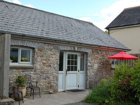 A stone cottage entrance with a table and chairs at Dryslwyn Cottage in Llandeilo