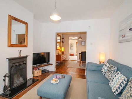 A living room with a blue sofa and ottoman near a fireplace and television at Owls Rest in Weymouth