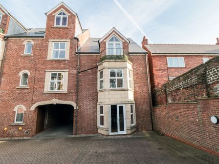 Exterior view of a multi-story brick building with arched windows and a balcony at Apartment 1 19 Cleveland Terrace Whitby