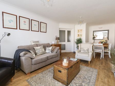 A living room with a sofa armchair wooden chest coffee table dining table and plants at Beach Side in West Bay