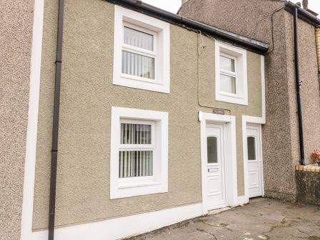 The exterior of a two-story house with two white doors and four windows at Clydfan Cottage in Llannerch-Y-Medd